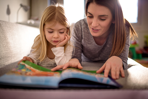 Maman passant du bon temps à lire à la maison avec son enfant